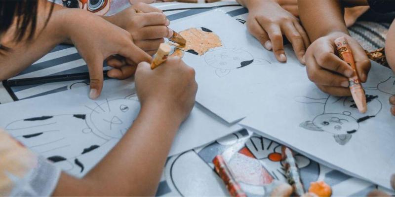 Children coloring cat drawings with crayons at a table