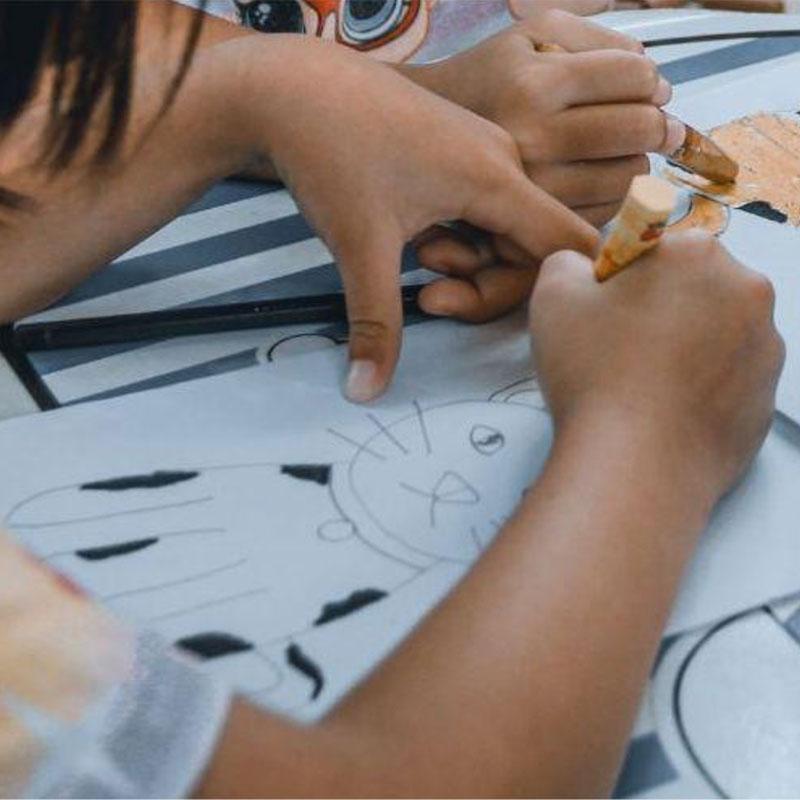 Children coloring cat drawings with crayons at a table