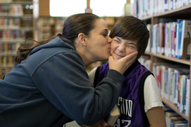 A woman kisses a child's cheek in a library.